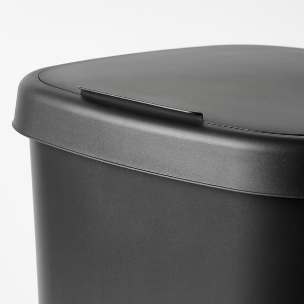 Close-up of sleek, black bin lid with smooth curves and small handle, showcasing its modern design and easy-to-clean surface.
