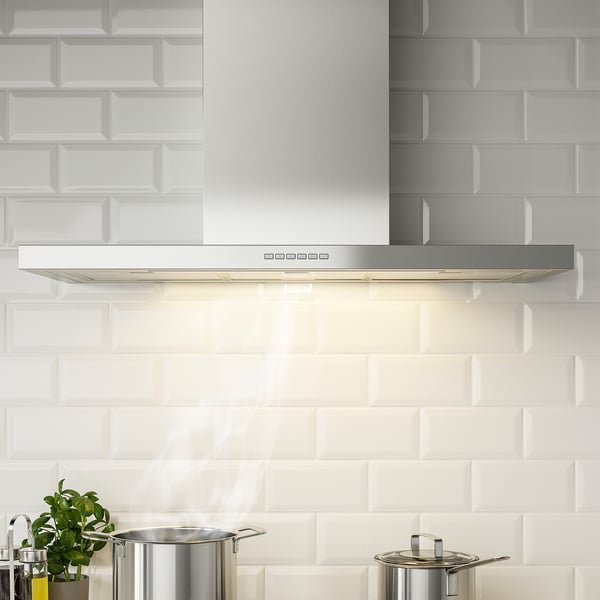 Modern kitchen with stainless steel range hood. Hood led lighting and grease philtres. Extracted fumes efficiently.
