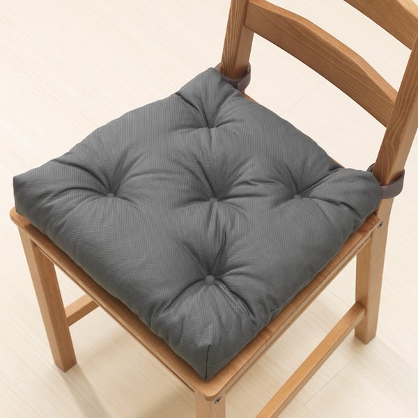 Square grey chair cushion with ties on light wooden chair.