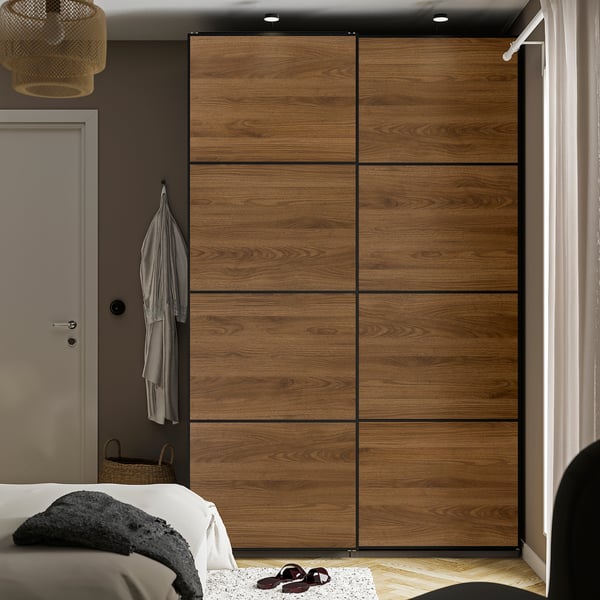 Modern bedroom MEHAMN large sliding wardrobe with wooden finish. It spans the wall, taller than the door and bed, with soft-close doors.