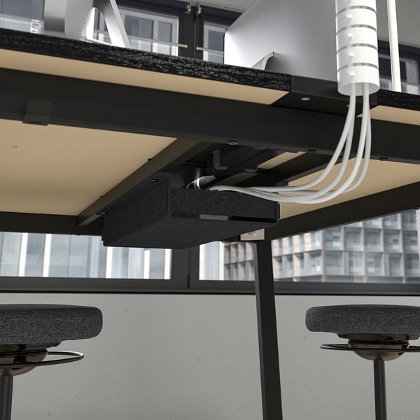 High conference table with integrated cable management and footrests, ideal for sitting or standing.