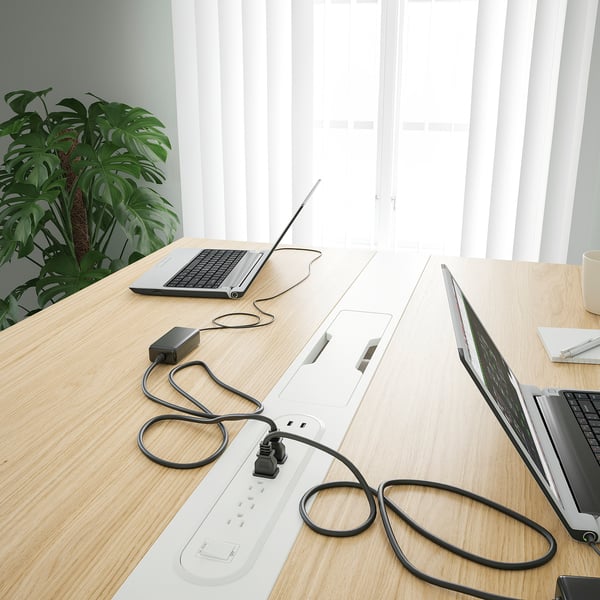 Conference table with built-in power strips and cable management for charging devices.