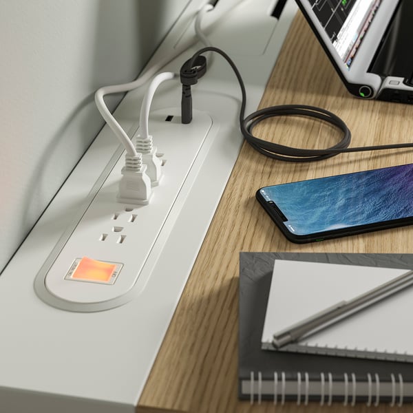 A multi-cable charging station on a desk with a smartphone, tablet, and notebook.