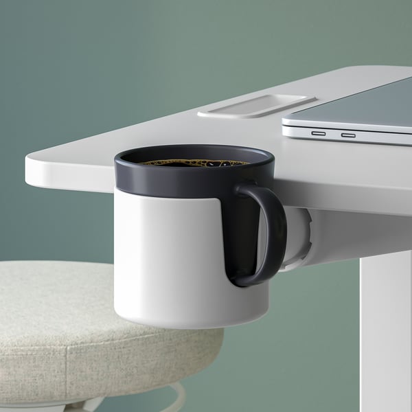 Adjustable laptop table with mug holder, suitable for sitting or standing.