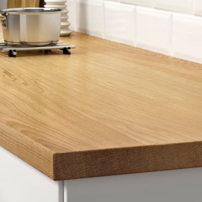 Wooden kitchen counter with smooth grain. Stainless steel stove in background.