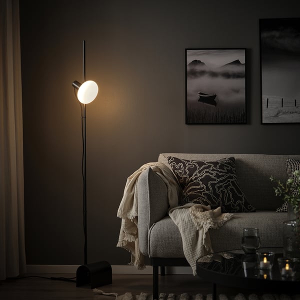 Modern living room with MOLNART lamp, couch, and wall photos.