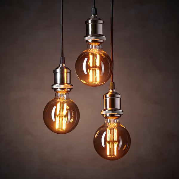 Three spherical edison-style bulbs with warm, glowing filaments hang from metal fixtures, emitting a soft, inviting light.