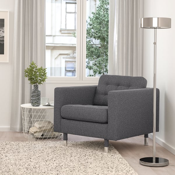 Modern living room with MORABO grey armchair, sleek floor lamp, side table, and large window. Cosy decor with minimalistic design.