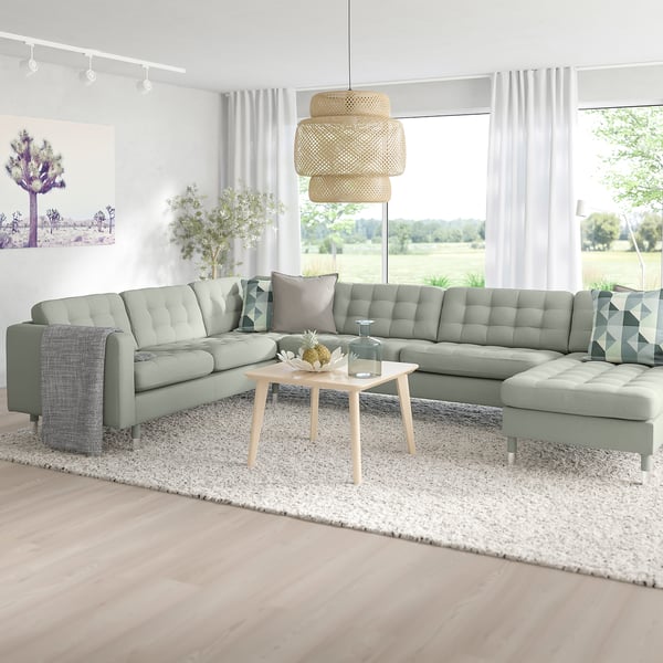 Cosy living room with sage green MORABO sofa, wooden coffee table, wicker pendant light, and scenic window view.