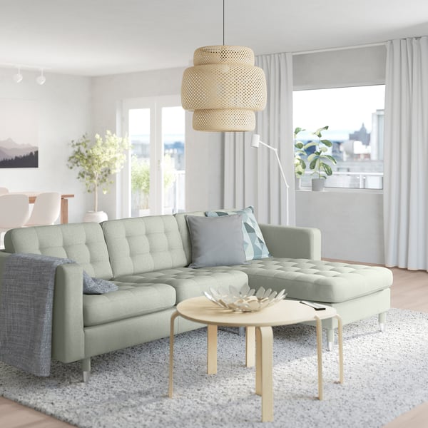 Modern living room with green sofa, wooden coffee table, large window, and cosy rug.