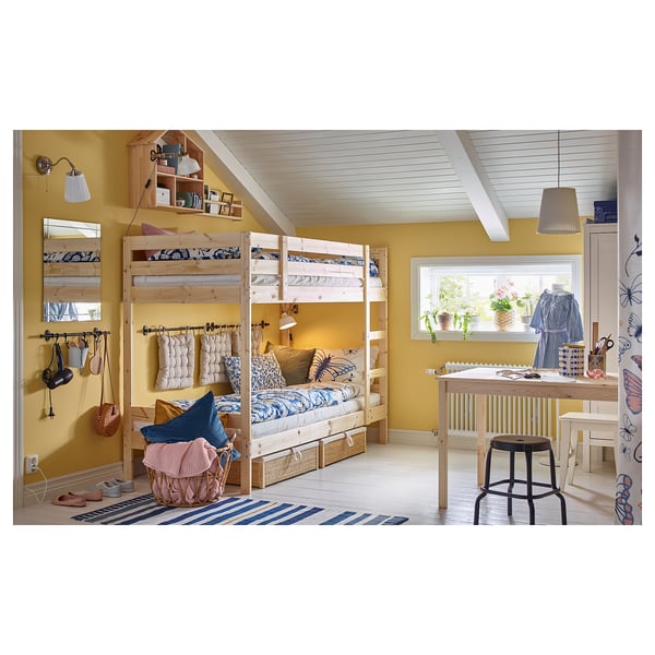 A cosy yellow kids room with a wooden bunk bed, blue & white decor, a desk area, and a striped rug.