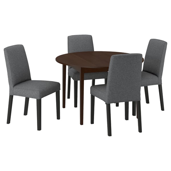 Modern dark brown round dining table with four grey upholstered chairs. Simple, sleek design.
