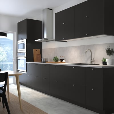 Modern black kitchen with dark cabinets, stainless steel appliances, and a sleek countertop. Large window for natural light.