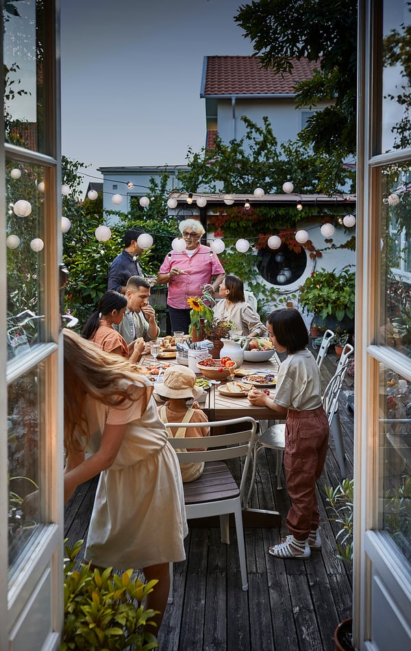 Family dining at acacia NORRMANSÖ table with herringbone pattern, patio setting.