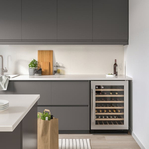 Mod. Kitchen with grey NUMRERAD wine fridge, holding 52 bottles, neatly placed under counter, next to sink and cutting board.