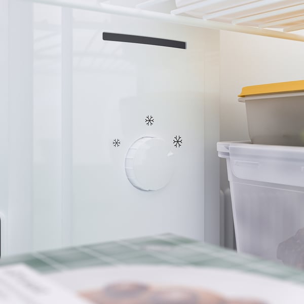 Open refrigerator revealing a white interior with an adjustable shelf, a light, and a freezer drawer.