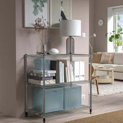 Silver OMAR storage unit in living room with books, lamp, boxes, beige sofa, and wooden table.