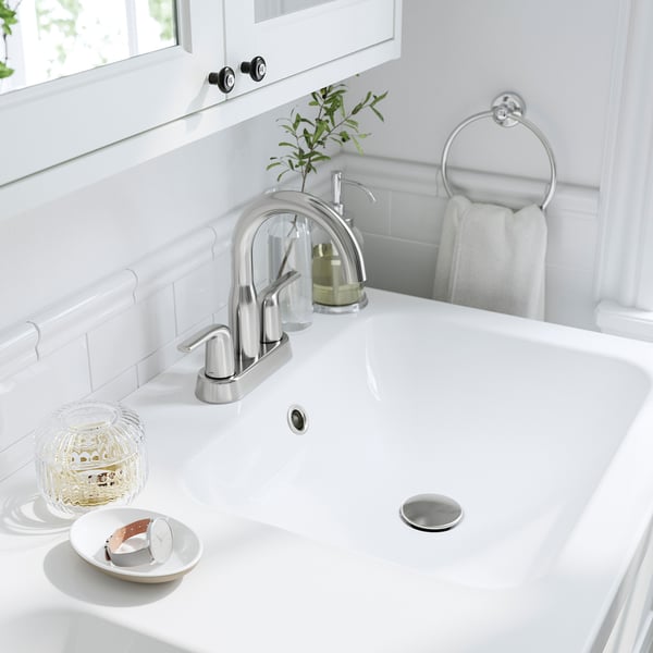 Modern bathroom sink with chrome tap, soap dispenser, and towel ring.