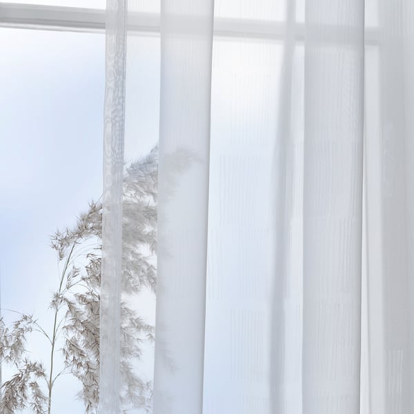 Sheer white curtains with pattern diffuse daylight, providing privacy, and a minimalist look.