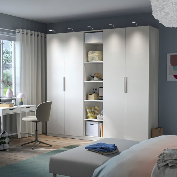 Modern bedroom with large PAX wardrobe, desk by window, blue walls, pendant lamp.