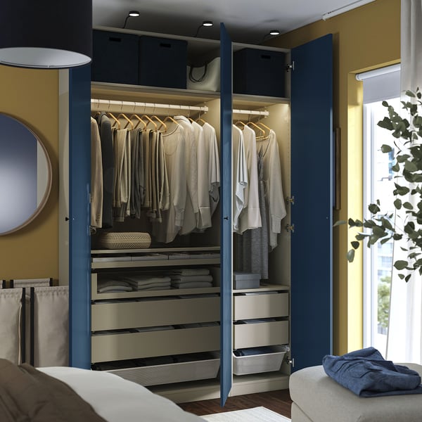 Open blue wardrobe with shirts on hangers, folded clothes in drawers, and clothes basket inside. Led lighting inside, on shelves.