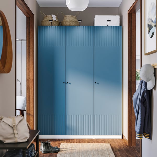 Modern entryway with blue PAX wardrobe, minimalist handles, baskets, and coats.