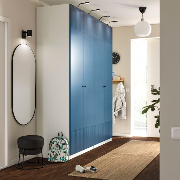 Calming blue PAX wardrobe with mirrors and minimalist handles. Includes seat, floral backpack, and cosy socks for organised living.