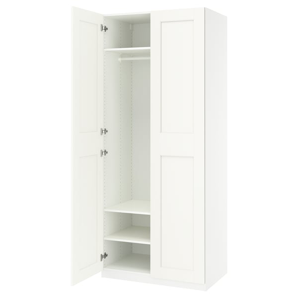 A white IKEA PAX wardrobe with open doors, revealing adjustable shelves and a hanging rod.