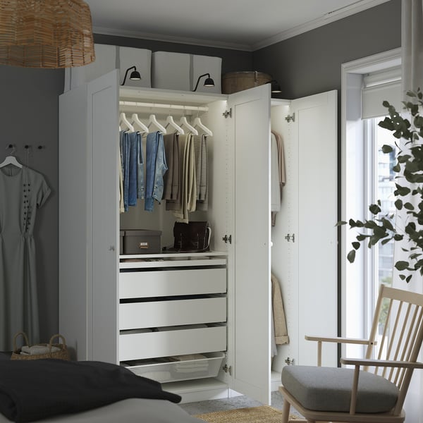 A modern wardrobe closet with open drawers, hangers, and clothes, showcasing organised storage solutions.