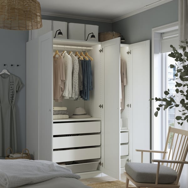 A modern white closet with drawers, hangers, and lit shelves displays clothes neatly, enhancing organisation and visibility.