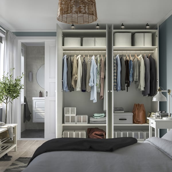 Neat bedroom with open wardrobe displaying clothes, shelves with folded garments, and organised storage.