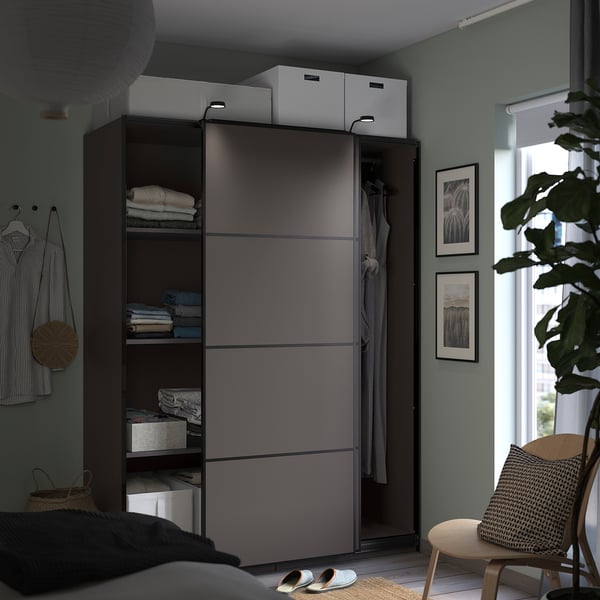 Modern bedroom a navy blue PAX wardrobe with sliding doors, organised with shelves and hanging space, set against green walls.