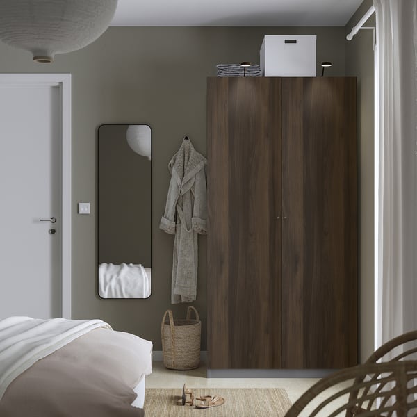 Modern bedroom with dark brown PAX wardrobe, mirror, and white accents.