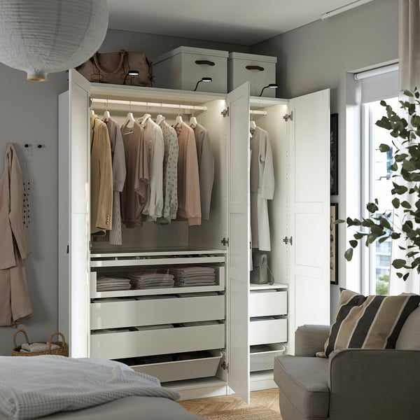 Modern wardrobe with colourful clothes, drawers, mesh baskets, by window.