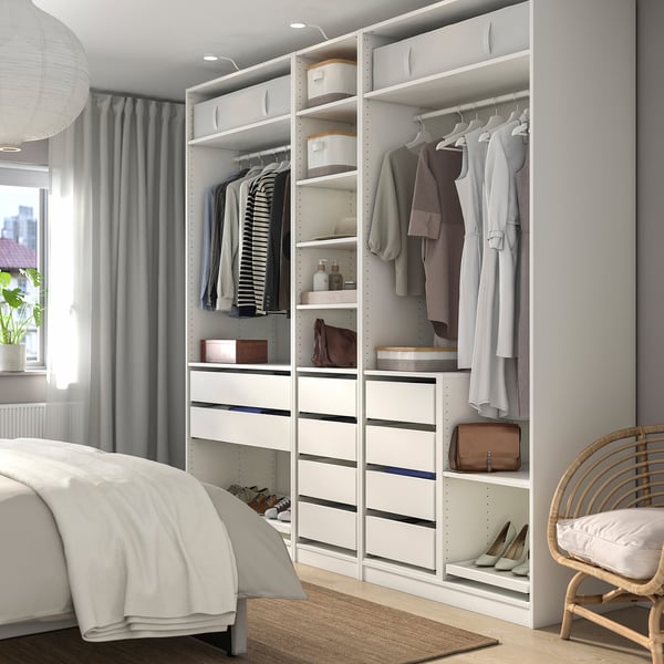 Modern white bedroom with large PAX wardrobe. Clothes hangers and storage shelves, matching bed and chair.