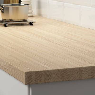 Light wooden countertop on a grey cabinet shows durable, sandable surface in kitchen setting.