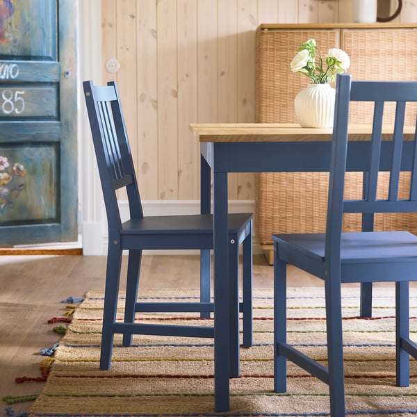 Dark blue pine chairs, vase flowers, rustic table. Cosy traditional setting.