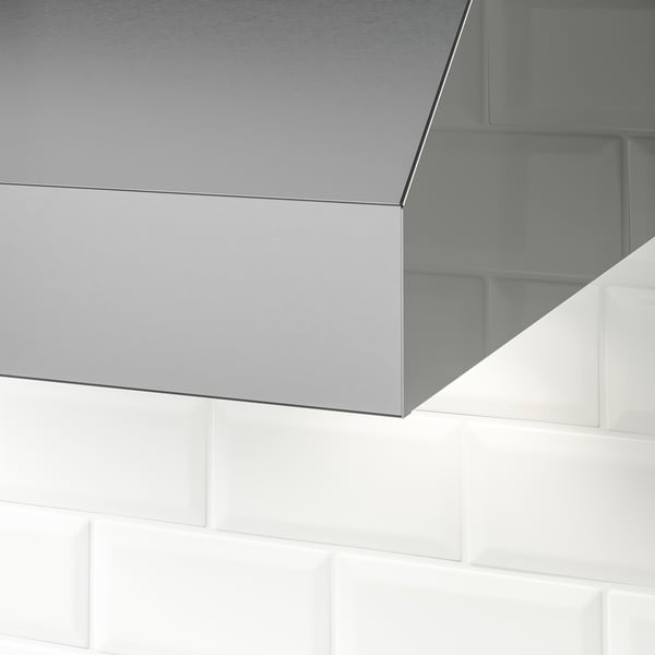 Stainless steel range hood mounted on tiled wall. Sleek, modern design with clean lines and reflective surface.
