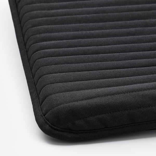 Close-up of POÄNG footstool cushion, showcasing its thick, padded texture and dark, durable fabric.