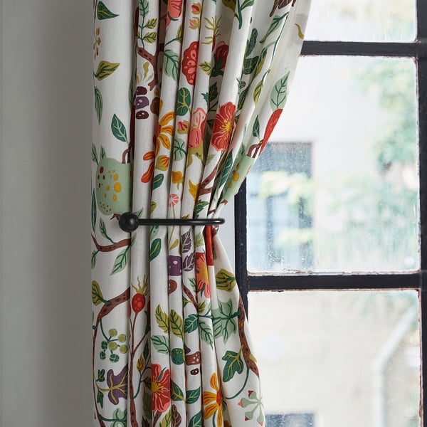 Floral curtain tie-backs in black, shaped with finials, holding curtains near a window.