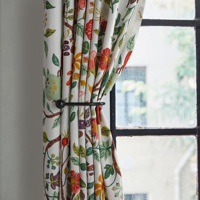 Floral curtain tie-backs in black, shaped with finials, holding curtains near a window.
