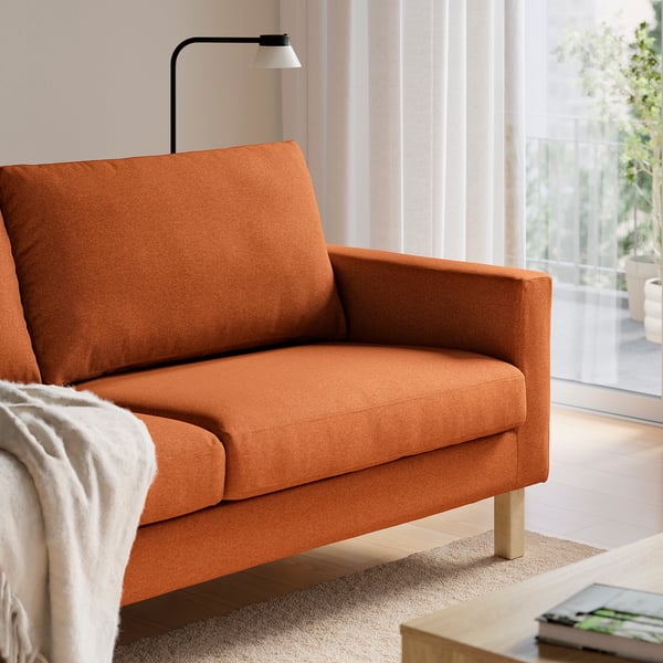 Bright living room with orange fabric sofa and floor lamp, highlighting comfortable seating and soft cushions.