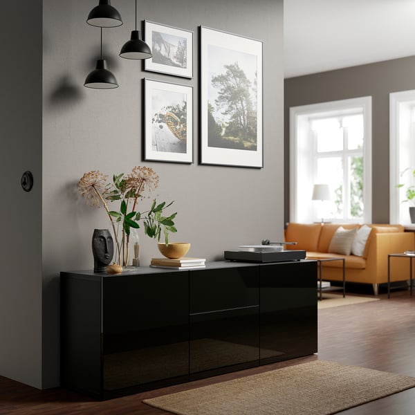 Modern living room with black glossy SELSVIKEN cabinet, styled with decor. Photos, lamps, and orange couch.