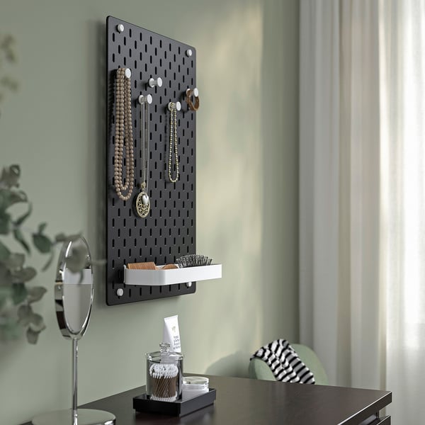 SKÅDIS pegboard holds jewellery, brushes, cotton swabs. Green wall, plant.