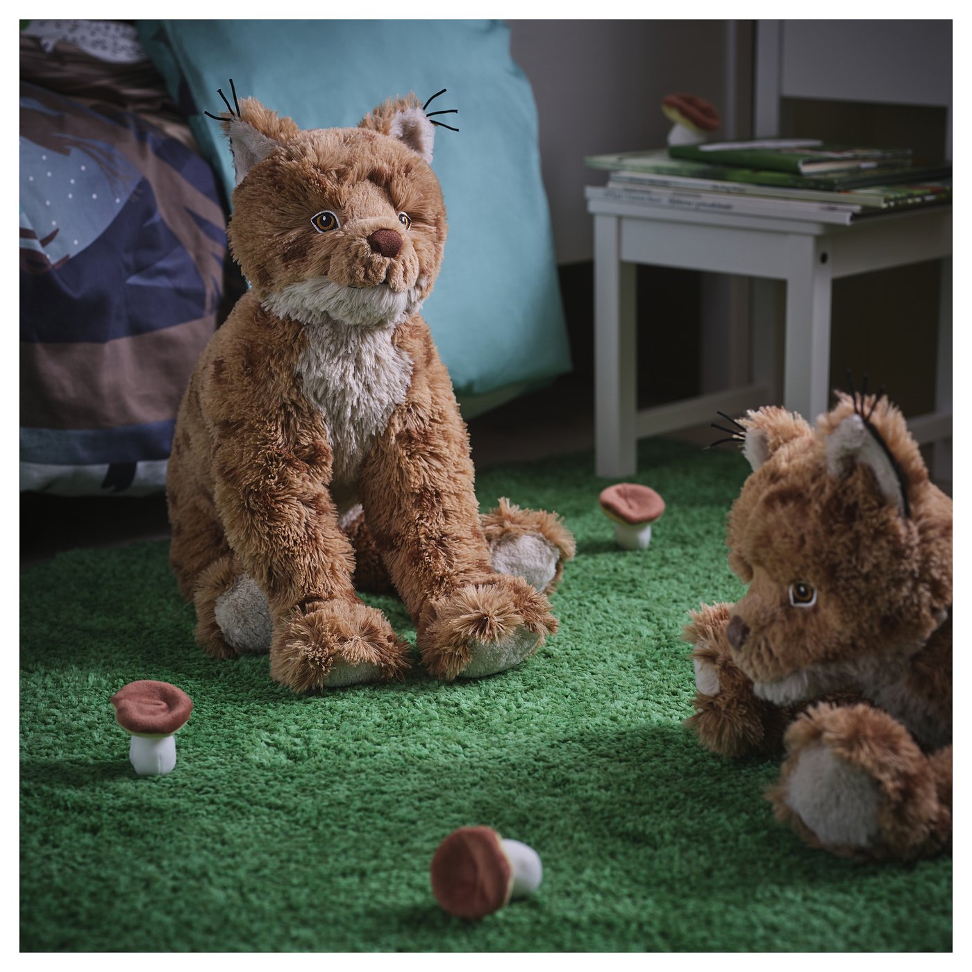 Two lynx plush toys on green carpet with mushrooms and books