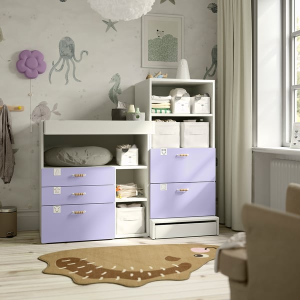 Kids room with lavender SMÅSTAD changing table & storage, ocean-themed decor, bear rug, functional & eco-friendly.