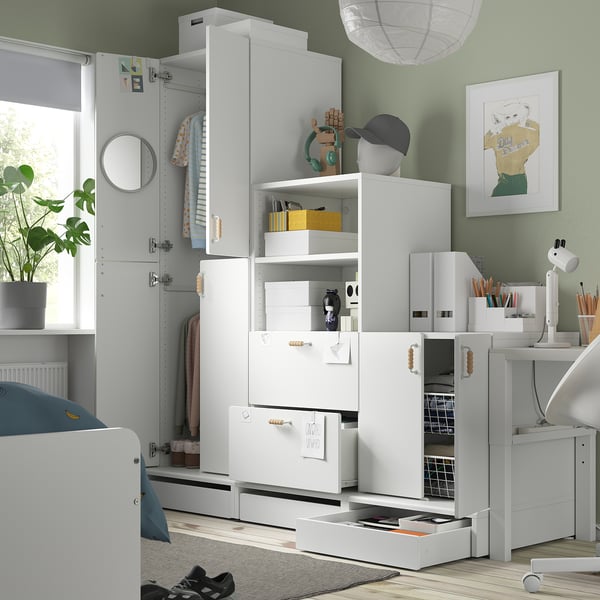 A childs room with a functional SMÅSTAD wardrobe. It holds clothes and has soft-closing doors. The room also includes a bed, desk, and art.
