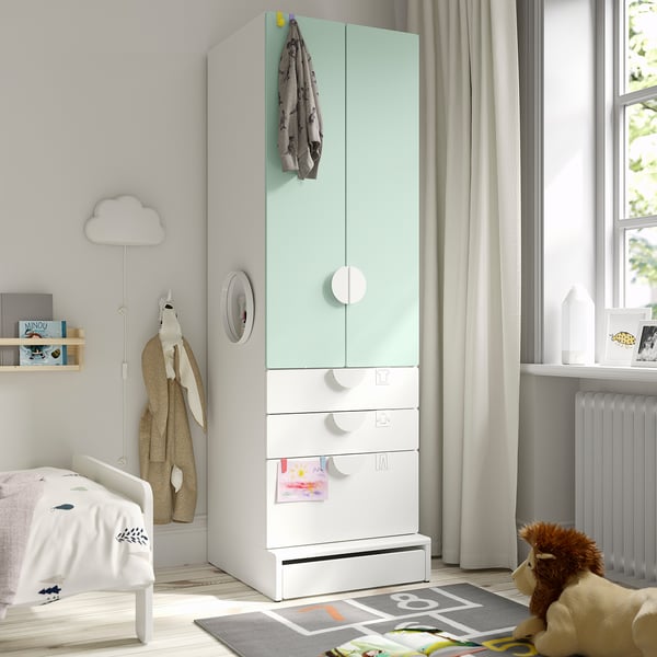 Kids room with tall green/white SMÅSTAD wardrobe. It has drawers, hanging space, soft-close doors, and toy/book decor.