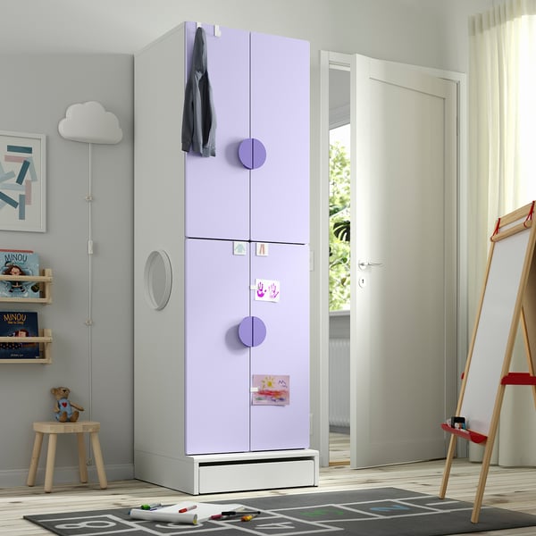 Kids room with tall lavender wardrobe, decorative handles, coat, and notes. Nearby small stool and door frame.