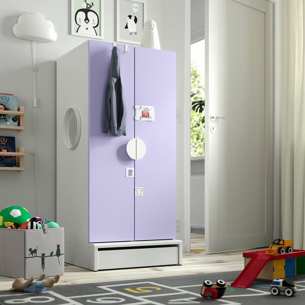 Kids room with lavender wardrobe, mirrors, hooks, & drawer. Surrounded by toys & books. Bright, natural light.